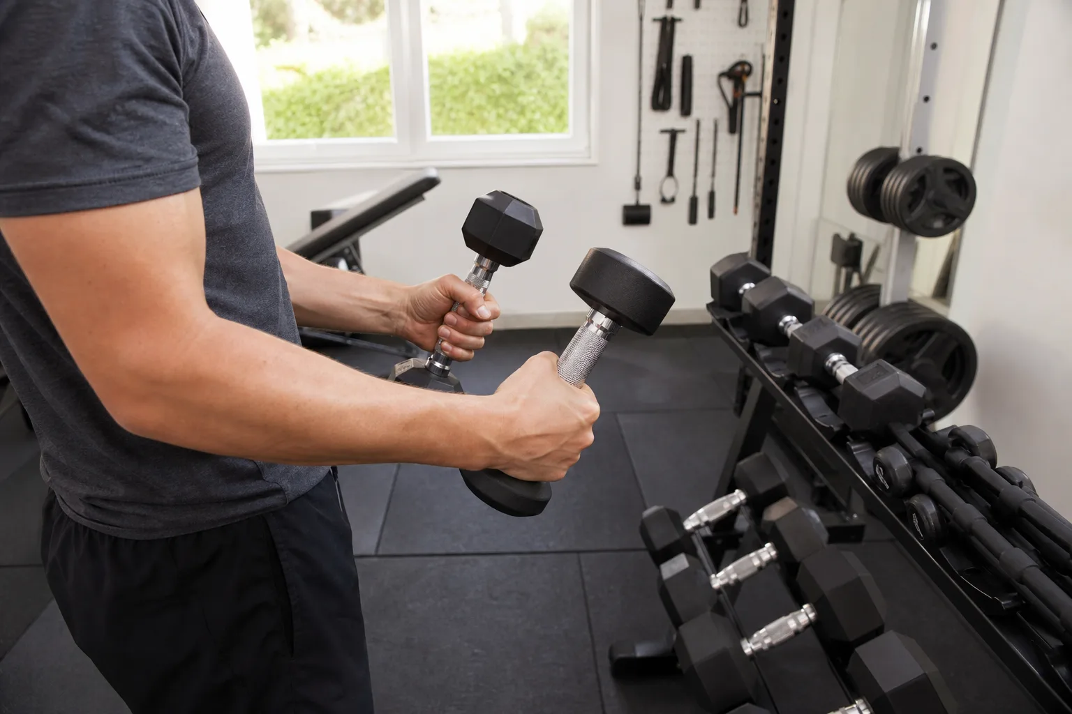 Händer känner på två hantelgrepp i garagegym